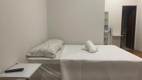 Duas camas num quarto branco com controlo remoto em HOSTEL ECONOMIC DIVINOPOLIS em Divinópolis