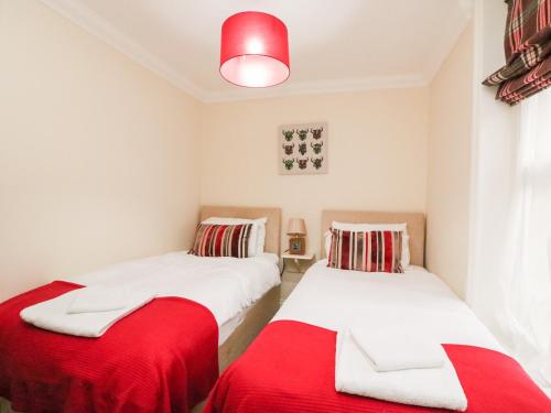 2 camas en una habitación con sábanas rojas y blancas en Harbour Watch Apartment 1, en Weymouth