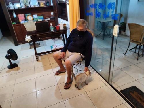 a man sitting on a chair with a dog at Pousada L'étage in Búzios