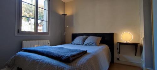 een slaapkamer met een bed met een blauwe deken en een raam bij Résidence Le Refuge Toy - 2 appartements T2 dispo - Tout compris in Luz-Saint-Sauveur