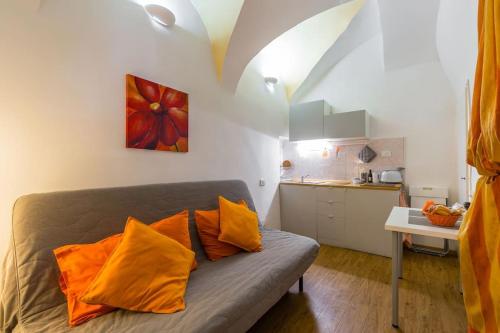 ナポリにあるCasetta Novaのソファ(オレンジ色の枕付)、キッチンが備わる客室です。