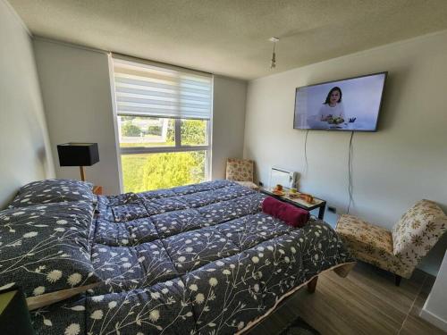 ein Schlafzimmer mit einem Bett und einem Stuhl und einem Fenster in der Unterkunft Departamento centro de Valdivia, Los Laureles 270, Isla Teja in Valdivia