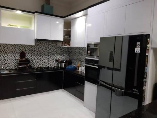 a kitchen with white cabinets and a black refrigerator at TITE homestay. Staycation feels @home in Salakan