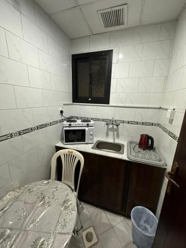 a small kitchen with a sink and a microwave at فندق المقام الراقي للشقق والغرف المفروشة in Makkah