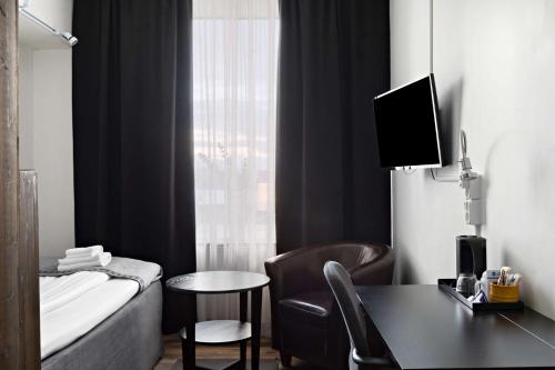 a hotel room with a bed and a desk and a tv at Best Western Hotel Arctic Eden in Kiruna