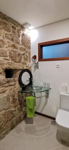 a bathroom with a glass sink and a stone wall at Casinha da Capela 1935 in Caminha