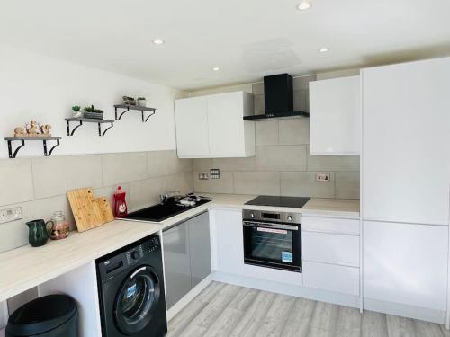 a kitchen with white cabinets and a washing machine at Lovely Modern 2 Bed Flat /w parking, close to town in Manchester