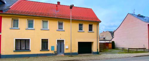 a yellow house with a red roof on a street at Ferienhaus Greiz in Greiz