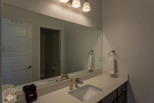 ein Badezimmer mit einem Waschbecken und einem großen Spiegel in der Unterkunft Lofts 13 4-bedroom Modern Loft Steps from the Pool in St. George