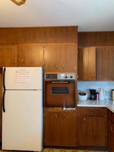 La cuisine est équipée d'un réfrigérateur blanc et de placards en bois. dans l'établissement #2 Cozy Queen size bedroom @New Brunswick NJ downtown, à New Brunswick