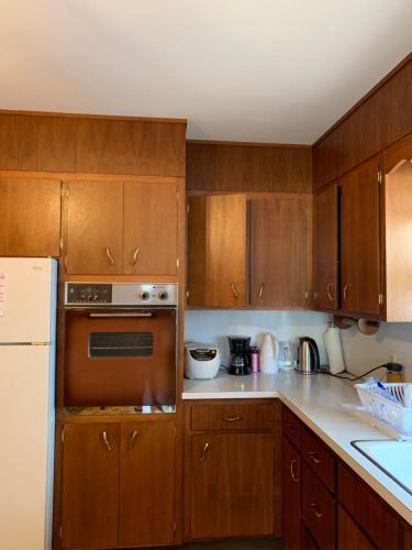 cocina con armarios de madera y nevera blanca en #2 Cozy Queen size bedroom @New Brunswick NJ downtown en New Brunswick