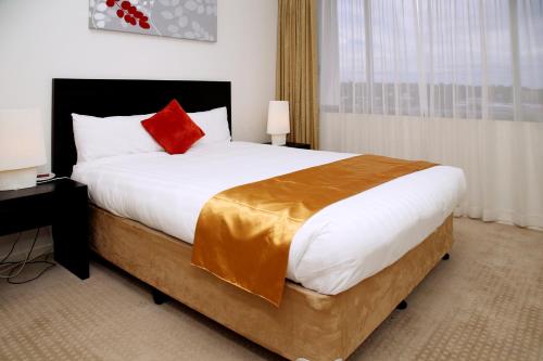 a bedroom with a large bed with a red pillow at Toowoomba Central Plaza Apartment Hotel Official in Toowoomba