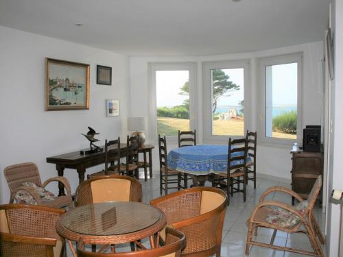 a dining room with a table and chairs and windows at Holiday Home Trebeurden by Pink Granite Coast in Trébeurden