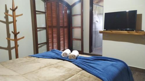 1 dormitorio con 1 cama con sábanas azules y TV en CANTINHO DO SOSSEGO, en Campos do Jordão
