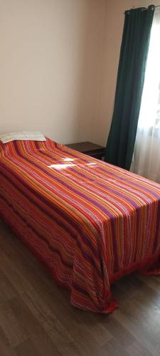 Una cama con una manta de colores encima. en Casa de la Loma en El Calafate