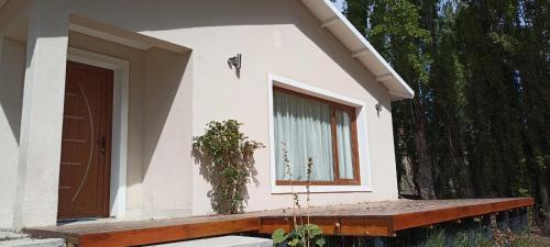 una pequeña casa blanca con ventana y banco en Casa de la Loma en El Calafate