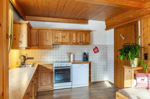 a kitchen with wooden cabinets and white appliances at Ferienwohnung Platzhirsch Panorama View Balkon, Gartensauna, Garten, Grillplatz in Stumm