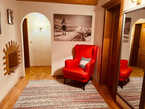 a hallway with two red chairs and a picture on the wall at Ferienwohnung Platzhirsch Panorama View Balkon, Gartensauna, Garten, Grillplatz in Stumm