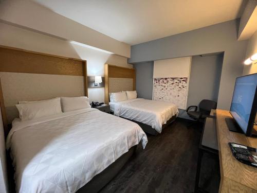 a hotel room with two beds and a flat screen tv at Holiday Inn Uruapan by IHG in Uruapan del Progreso
