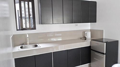 a kitchen with black cabinets and a sink and a refrigerator at Maria Cristesa Condotel 