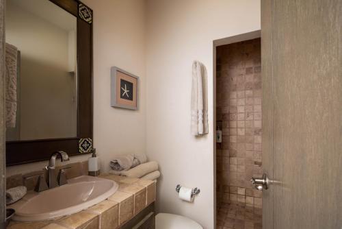 a bathroom with a sink and a toilet and a mirror at LC 1A- Beach Club & Housekeeping included - Golf Cart in La Paz