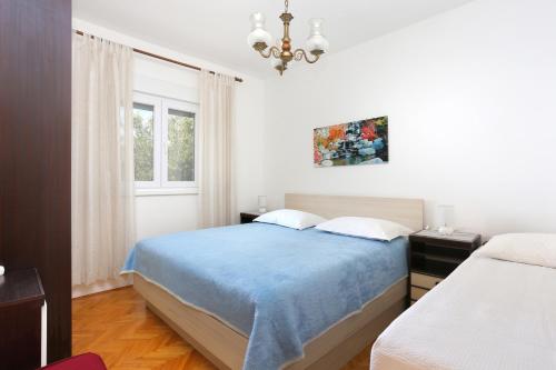 een slaapkamer met een blauw bed en een raam bij Apartments by the sea Seget Vranjica, Trogir - 18487 in Donji Seget