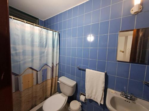 a blue tiled bathroom with a toilet and a sink at Sorokaima in Caracas