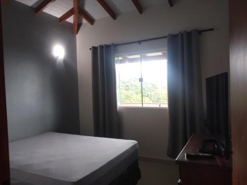 um quarto com uma cama e uma janela em Chalé Boa Vista em Ilhabela