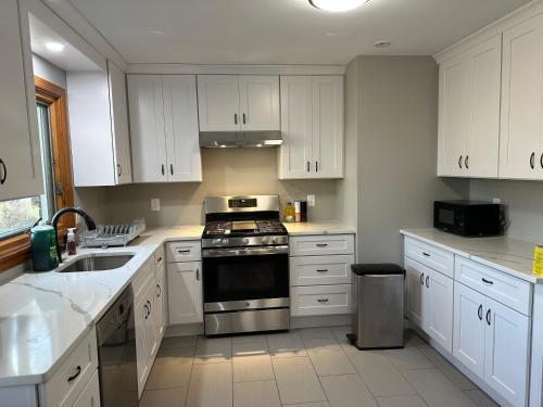 een keuken met witte kasten en een fornuis met oven bij M1 Queen Size BedRoom with desk near Rutgers U & hospitals in New Brunswick