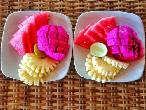 two plates filled with different types of fruit at Dreamy Eco Tree House by 7 Waterfalls in Ambengan