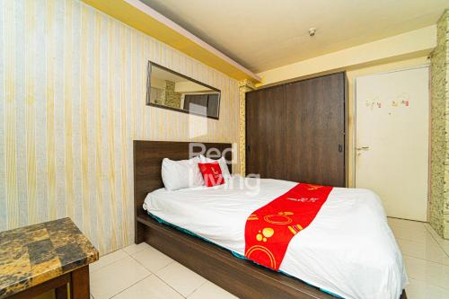 um quarto com uma cama com um cobertor vermelho em RedLiving Apartemen Kalibata City - Homy Jasen Tower Jasmine em Jacarta