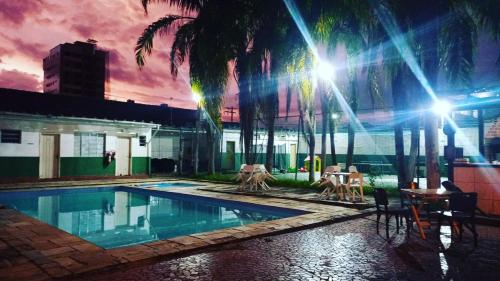 a swimming pool with palm trees and a building at Pousada Praia Grande - Rua Ernesto Vergara ,511 in Praia Grande