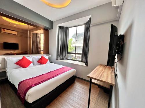 a bedroom with a bed with red pillows and a television at Bayu 23 Hotel in Kota Kinabalu