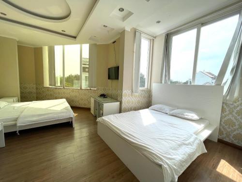 a bedroom with two beds and two windows at MILAND HOTEL in Can Tho