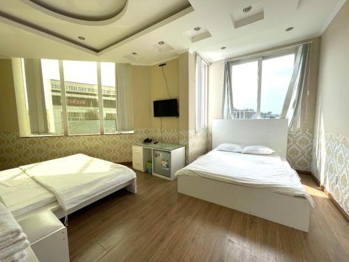 a bedroom with two beds and a large window at MILAND HOTEL in Can Tho
