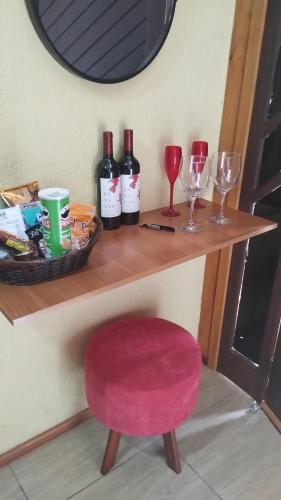 een tafel met wijnglazen en een rode kruk bij Chalés Pedacinho do Céu entre Penedo e Visconde de Mauá in Resende