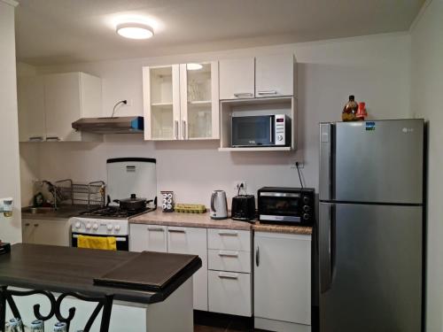 a kitchen with white cabinets and a stainless steel refrigerator at Acogedor, cómodo y central. in La Serena