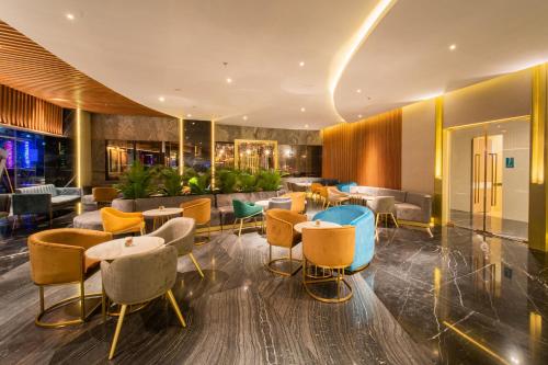 a lobby of a hotel with tables and chairs at Pentacity Hotel Balikpapan in Balikpapan