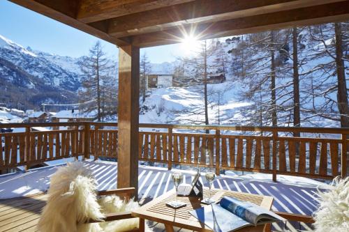 a wooden porch with a table and a view of a mountain at La Vue Luxury Living Apartments in Zermatt