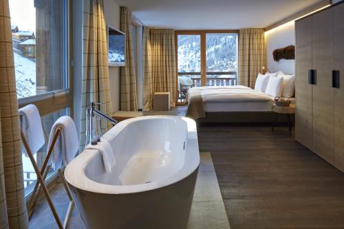 a bathroom with a tub and a bedroom with a bed at La Vue Luxury Living Apartments in Zermatt