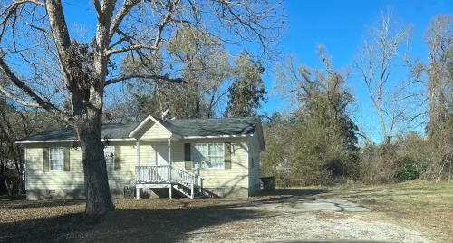a small white house with a tree in front of it at 3 Bed 2 Bath House, Quiet & downtown Smart TVs in all rooms, Whole house to yourself in Havelock