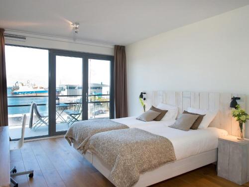 een slaapkamer met een groot bed en een balkon bij Modern apartment in the harbor of Schevening in Scheveningen