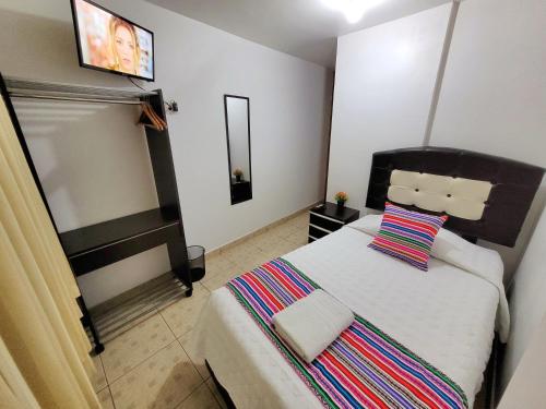 Hostal EL VIAJERO en Ollantaytambo في أولانتايتامبو: غرفة نوم بسرير كبير ومخدة مخططة