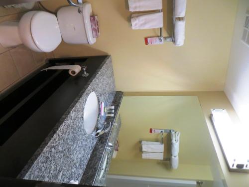 a bathroom with a sink and a toilet and towels at Super 8 by Wyndham Saskatoon Near Downtown in Saskatoon