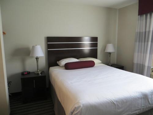 a hotel room with a bed with a red pillow on it at Super 8 by Wyndham Saskatoon Near Downtown in Saskatoon