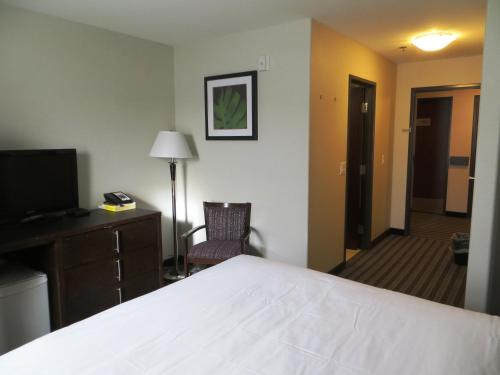a hotel room with a bed and a desk and a television at Super 8 by Wyndham Saskatoon Near Downtown in Saskatoon