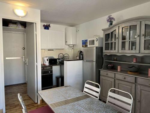 une cuisine avec une table et un réfrigérateur blanc dans l'établissement Studio Cabine Près Plage avec Parking et Animaux Acceptés - FR-1-702-13, au Cap d'Agde