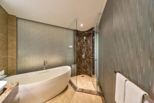 a bathroom with a large tub and a sink at Ashley Wahid Hasyim Jakarta in Jakarta