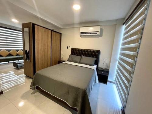 ein Schlafzimmer mit einem Bett und einer Couch in einem Zimmer in der Unterkunft Apto moderno y cómodo cerca del Mall Las Brisas in Santa Cruz de la Sierra