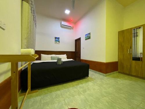 a bedroom with a black bed in a room at LETS GO HURAA in Huraa